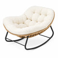Silla mecedora tipo lounge tapizada en tejido crema con base metálica negra y estructura de ratán sintético estilo moderno